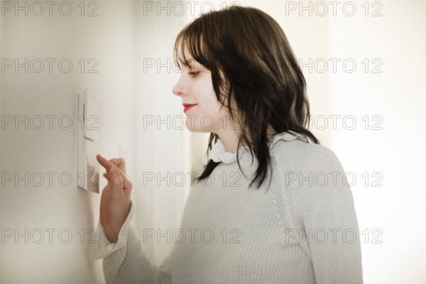 Woman operates a smart switch on the wall, save energy, environmentally friendly
