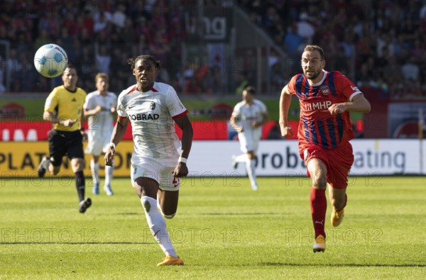Football match, Junior ADAMU SC Freiburg left and Benedikt GIMBER 1. FC Heidenheim chase the ball in a sprint in a duel, referee Benjamin Brand can be seen in the background, Voith-Arena football stadium, Heidenheim