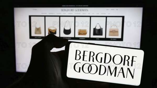 Stuttgart, Germany, 02-26-2024: Person holding cellphone with logo of US luxury department store company Bergdorf Goodman Inc. in front of webpage. Focus on phone display, Europe