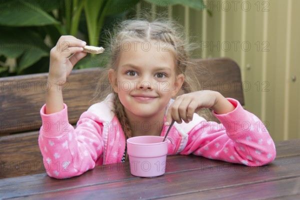Girl sitting at a wooden table on the porch, and breakfast