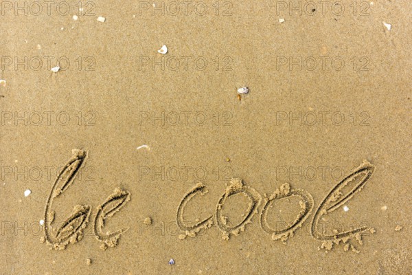 Be cool written on the beach. sand background