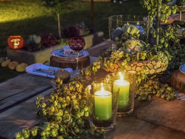 Two green candles glowing on a decorated outdoor table, surrounded by flowers and other decorative elements in an evening atmosphere, borken, münsterland, Germany, Europe
