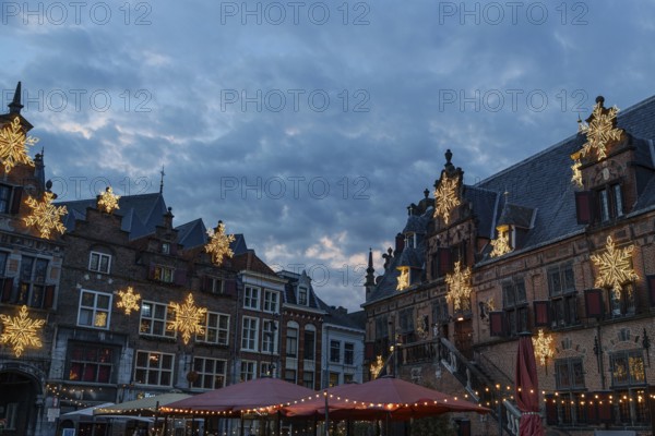 Historic buildings on a market with Christmas lights and cloudy sky at night, nijmegen, the netherlands