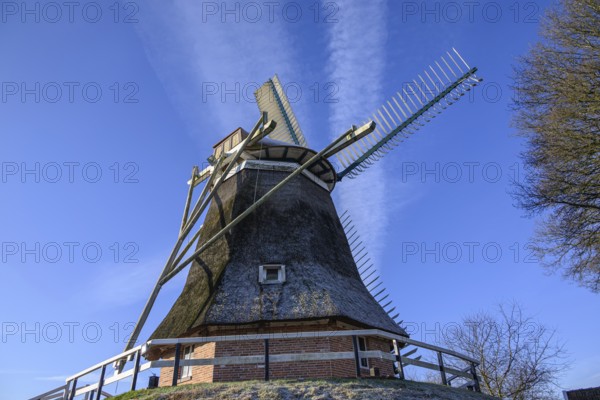 General view of a windmill with broad wings and blue sky, empty, east frisia, germany