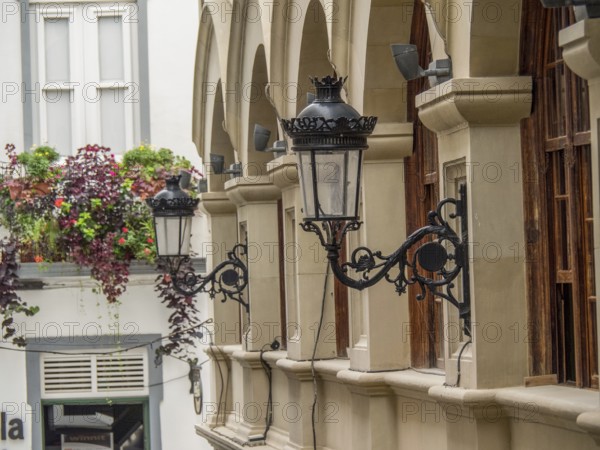 Historic lanterns hanging on the wall of a building with arches and plants in the city, la palma, canary islands, spain