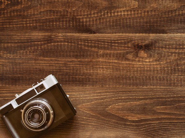 Wooden table background with old vintage camera. Flat lay or top view
