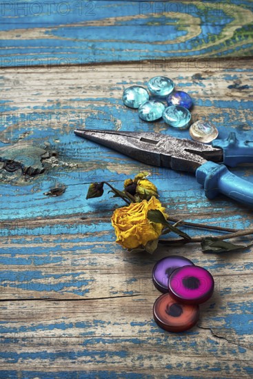 Beads, pliers, and other needlework accessories on outdated turquoise wooden background
