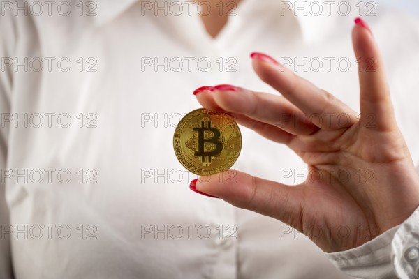 Virtual cryptocurrency money Bitcoin golden coin in the left hand of a woman with red nail polish. The future of money