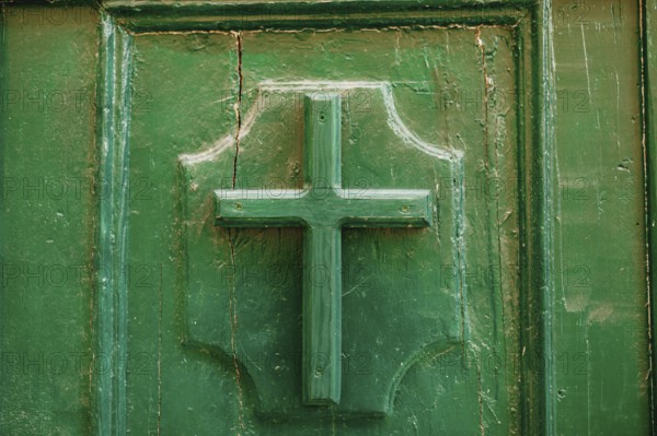 The entrance to the church. Cross on a wooden door green