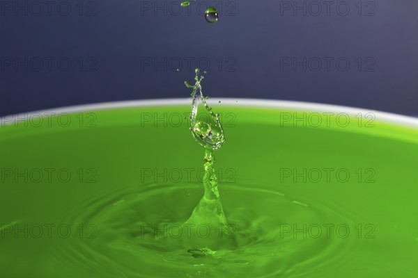 A drop of water forms a splashing sculpture on green liquid, water droplets, collision, high-speed photography, concept, water figures