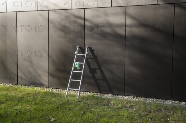 Cleaning crew equipment left on grass lawn in front of modern architecture building facade during daytime
