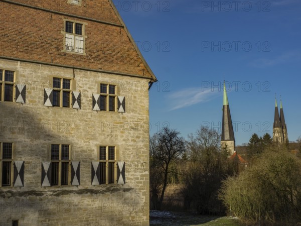 Historic building with shutters, and a church in the background on a clear day, billerbeck, münsterland, germany