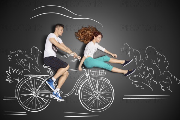 Happy valentines love story concept of a romantic couple against chalk drawings background. Male riding his girlfriend in a front bicycle basket
