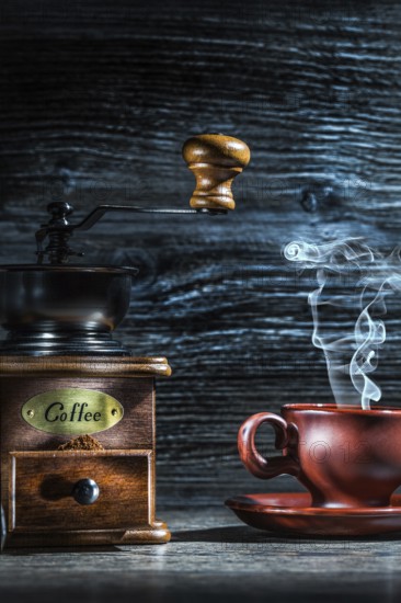 Steamy coffee cup and mill on vintage wood