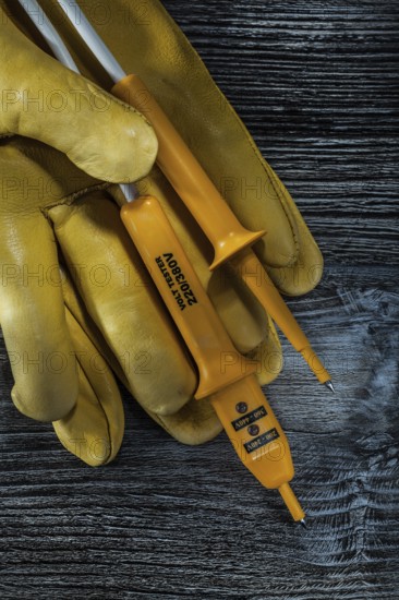 Set of electric tester safety gloves on vintage wooden board