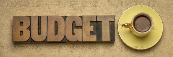 Budget word in vintage letterpress wood type block against textured bark paper with a cup of coffee, business or personal finance concept