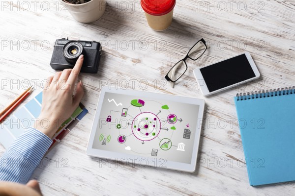 Blogger sitting at desk with tablet computer and camera. Mobile smart devices in business processes. Business occupation and innovation. Corporate office workplace with business woman at wooden desk