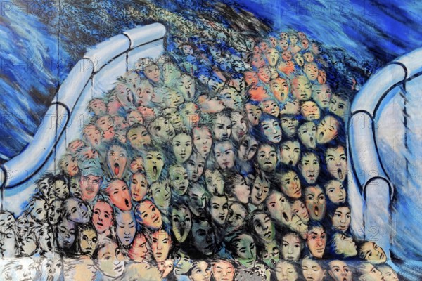A multitude of surreal painted faces crowd together, surrounded by blue and bright colours, Graffiti on the Berlin Wall in the East Side Gallery, Berlin, Germany, Europe, Abstract graffiti showing a surreal scene with many colourful details and faces, East Side Gallery, Warschauer Straße, Europe