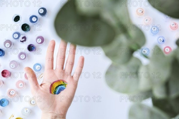 Rainbow LGBTQ flag painted on hand. Support for lgbt community. Honour of pride month. Connecting people, touching hands. Multi colored hands art creativity, discrimination