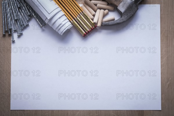 Wooden meter blueprints sheet of paper nails claw hammer woodworking dowels on wood board copy space construction concept