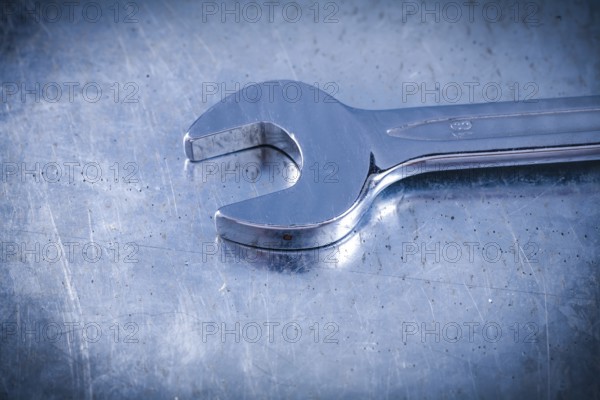 Stainless spanner wrench on scratched metallic background top view construction concept