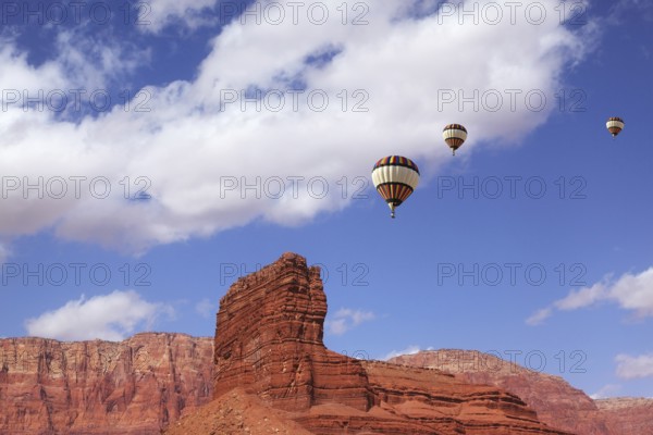 Huge balloons with the passenger basket flying over the picturesque cliffs of red sandstone
