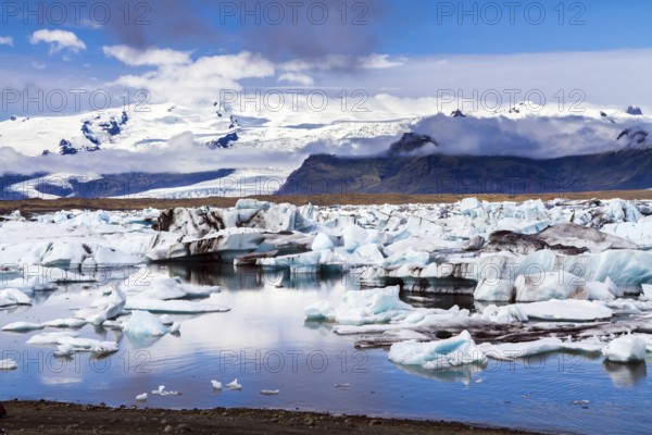 Cold day in July. Arctic Circle, Iceland. White and blue icebergs and ice floes reflected in the water. Iceland. The lagoon Jokulsaurloun. The concept of extreme, northern and photo tourism