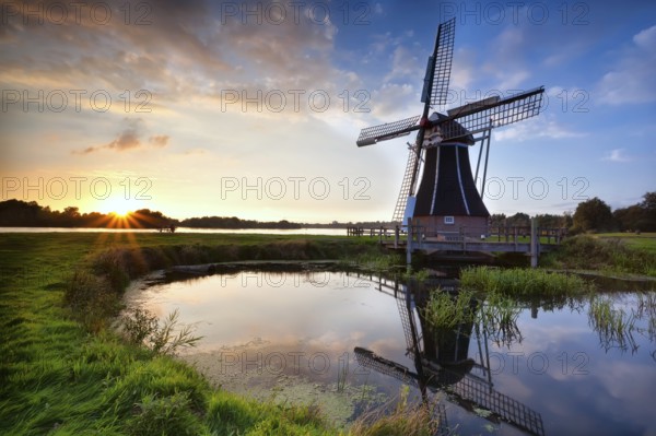 Charming Dutch windmill reflected in lake at sunset, Holland