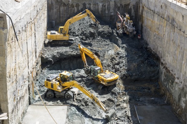 Excavators dig at a construction site of a street and a subway. Baggers transport dirt to a higher level to make room for the subway digging machine. Working fast and efficient