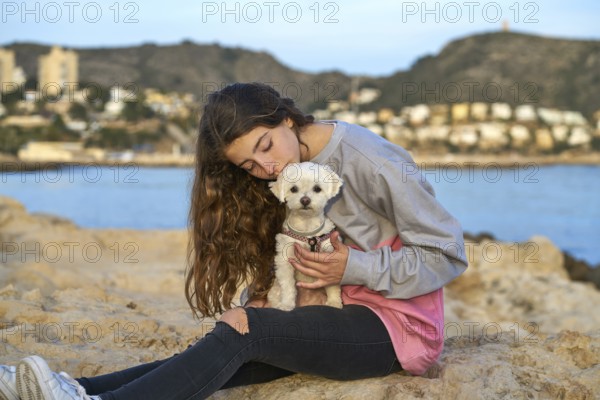 Girl playing with maltichon puppy dog in the beach