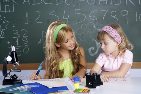 Kids students in classroom helping each other at school desk