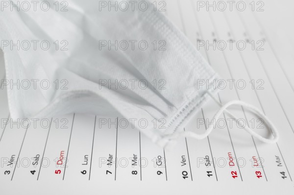 Montly calendar with self protection face mask. Coronavirus concept. Beginning / end of the pandemic. Deadline concept with sheet of monthly calendar. Coronavirus COVID-19. Copy space. Selective focus