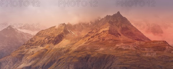 Swiss Alps mountain peaks dramatic sunset view, cloudy sky in Switzerland