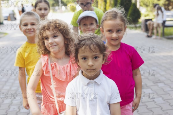 Portrait of happy preschool kids posing closely together outdoors, looking at camera. Lovely boy and girls outdoors at summer camp