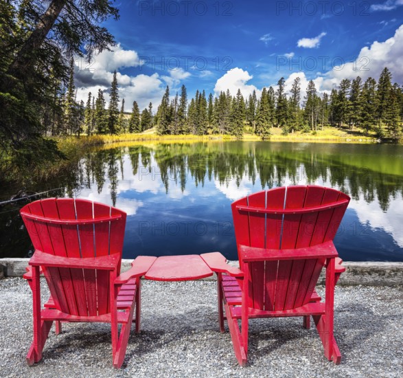 Jasper National Park in the Rocky Mountains. Two red plastic chairs on the lake. On shores of the lake grow coniferous forests