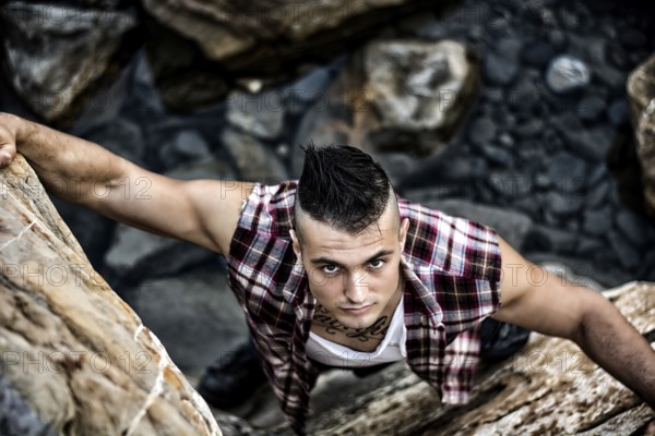 Three Quarter Shot of an Attractive Athletic Young Man Climbing a Rock at the River or by the Sea or Ocean