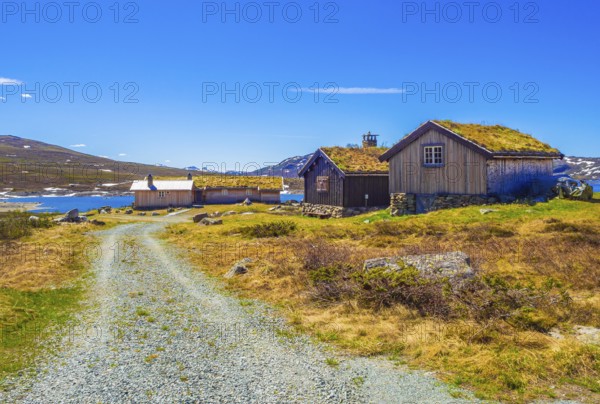 Amazing Vavatn lake panorama rough landscape view cottages and mountains with snow during summer in Hemsedal Norway