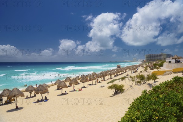 Umbrellas on a sandy beach with azure blue water on a sunny day near Cancun, Mexico, Central America