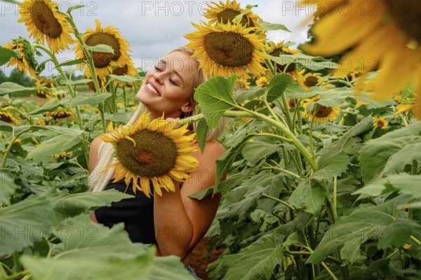 A stunning blonde model gracefully poses in a vibrant sunflower field, basking in the warmth of a summer day. The golden blooms surround her, creating a joyful and radiant outdoor scene, McConnells, United States of America