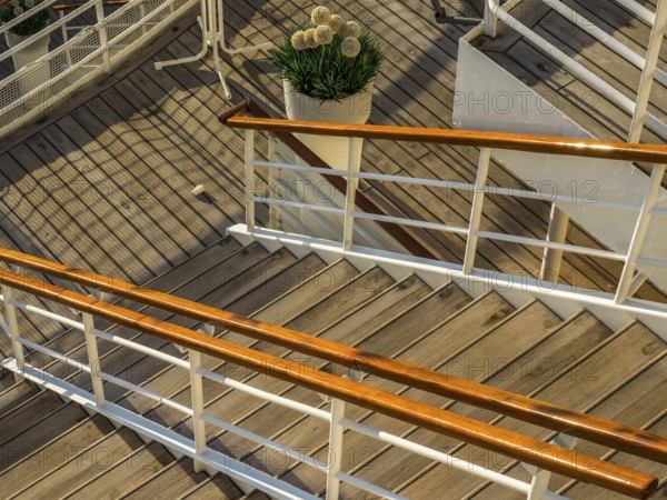 Wooden staircase with railing on a ship deck and a decorative potted plant with flowers, stockholm, baltic sea, sweden, scandinavia