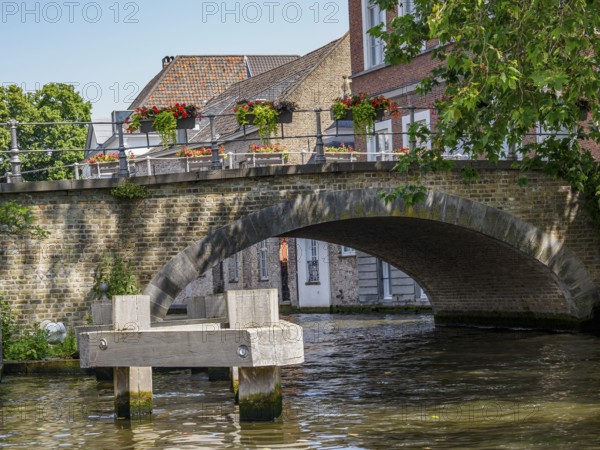 Picturesque stone bridge with flower boxes in bloom over a quiet canal, Bruges, Flanders, Belgium, Europe