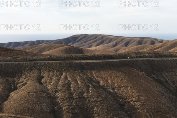 Gentle brown hills under a blue sky in an arid landscape. Viewpoint Mirador Astronomico de Sicasumbre around Pajara, Fuerteventura, Canary Islands, Spain, Europe