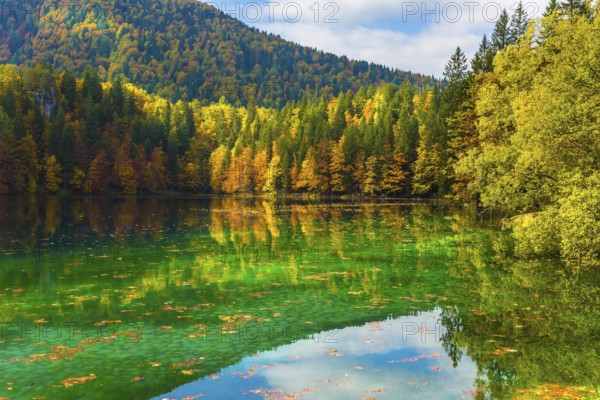 Flood after rain. Scenic reflections of multicolored forests in the smooth water of the lake. The quiet lake in Northern Italy, Lago de Fusine. Concept of cultural and ecological tourism