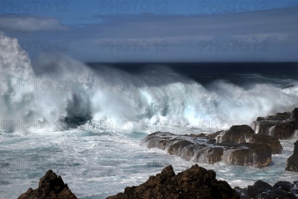 Waves breaking thunderously on the sharp rocks of a cliff. Landscape format. Waves breaking thunderously at the rugged rocks of a cliff. Horizontal format
