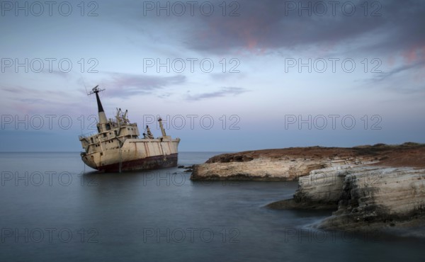 Abandoned Ship on the rocky coast with beautiful blue and orange morning colors creating an exotic seascape at Paphos area in Cyprus