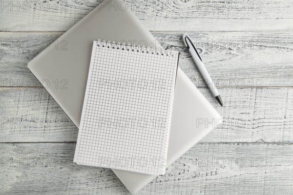 White paper Notepad and laptop on vintage shabby white wooden background. the view from the top. flat lay