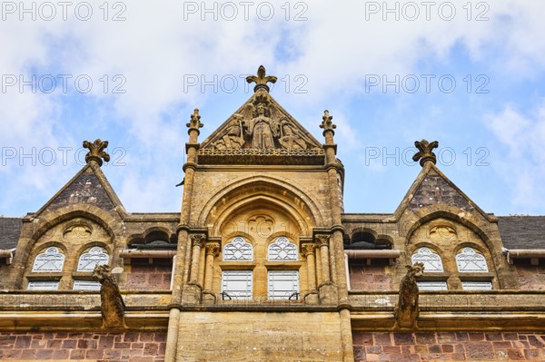 Detailed, gothic facade sculptures of a historic manor house against a clear blue sky. Knightshayes, Tiverton, Devon, England, Great Britain, United Kingdom, Europe