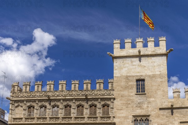Tower with the flag of Valencia on the richly decorated brick building of the Algemesí School in Pl. del Mercat with blue sky in the background in the centre of the old town, Valencia, Autonomous Community of Valencia, Province of Valencia, Spain, Europe