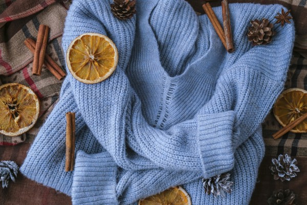 Blue sweater and cinnamon sticks and anise star. Dry slices of citrus orange and cones. Hot winter cocktail. Christmas, Thanksgiving drinks. Autumn, grog, hot sangria, mulled wine. Festive holiday flat lay atmosphere