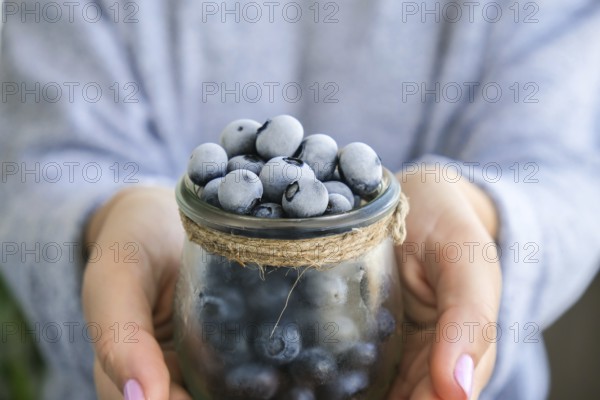 Woman holding bowl with Frozen blueberry fruits. Harvesting concept. Female hands collecting berries. Healthy eating concept. Stocking up berries for winter Vegetarian vegan food. Dieting nutrition